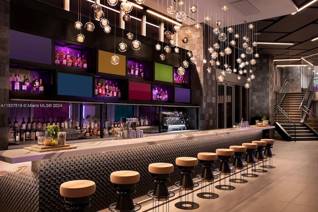 bar featuring a high ceiling and light stone counters