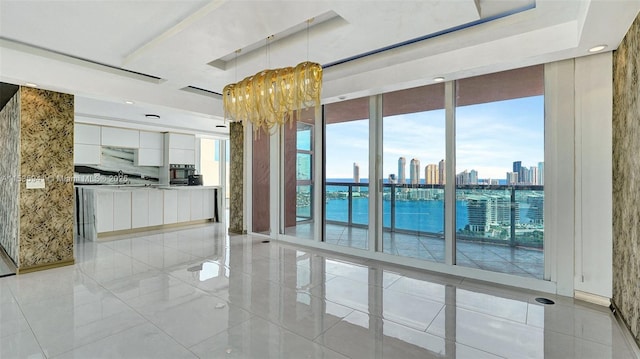 unfurnished room featuring a wall of windows, an inviting chandelier, a wealth of natural light, and a tray ceiling