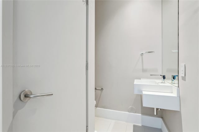 half bath featuring baseboards, toilet, and tile patterned floors