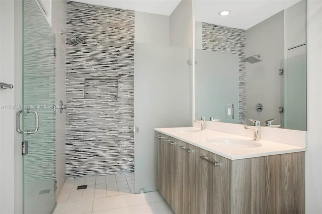 bathroom with double vanity, tile patterned flooring, a shower stall, and a sink