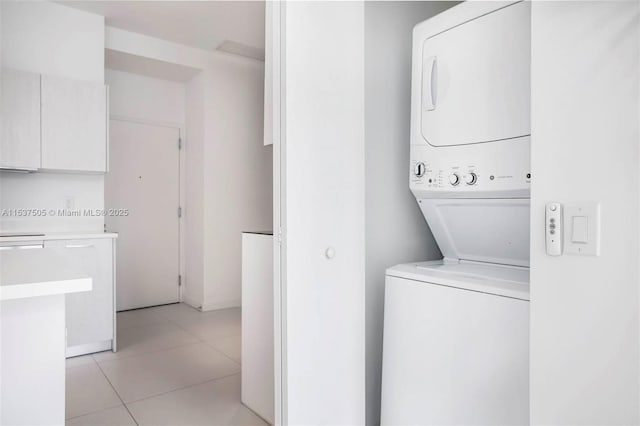 laundry area with laundry area, light tile patterned floors, and stacked washer and clothes dryer