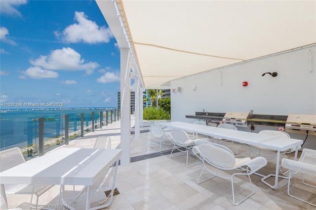 view of patio featuring a water view, a grill, and outdoor dining space