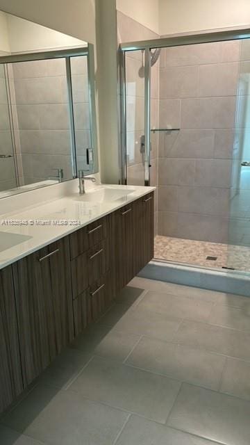 bathroom featuring tile floors, a shower with shower door, and dual vanity