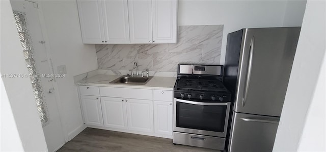 kitchen with white cabinets, dark hardwood / wood-style floors, stainless steel appliances, decorative backsplash, and sink