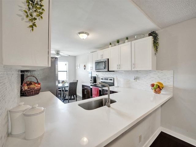 kitchen featuring ceiling fan, sink, stainless steel appliances, a textured ceiling, and white cabinetry