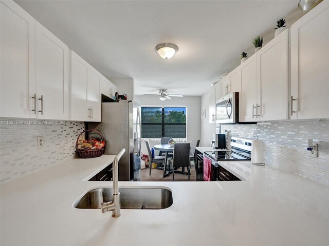 kitchen with stainless steel appliances, ceiling fan, tasteful backsplash, white cabinetry, and sink