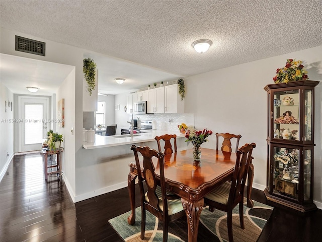 dining room with a textured ceiling, dark hardwood / wood-style floors, and sink