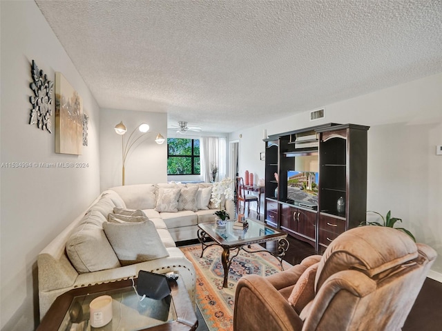 living room featuring hardwood / wood-style flooring, ceiling fan, and a textured ceiling