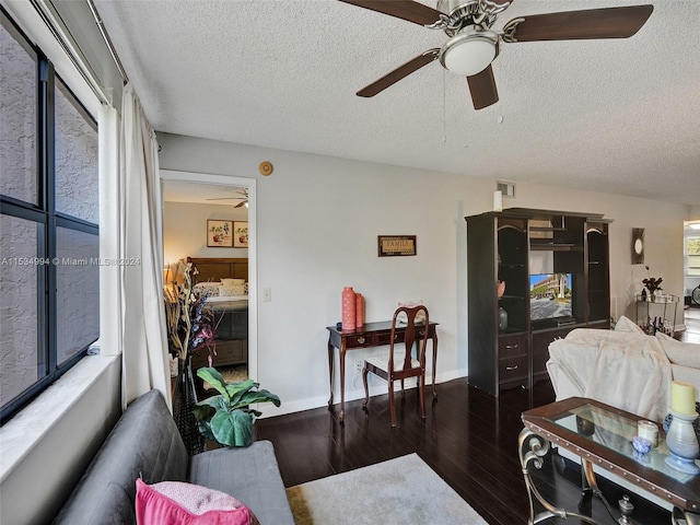 living room with a textured ceiling, ceiling fan, and dark hardwood / wood-style floors