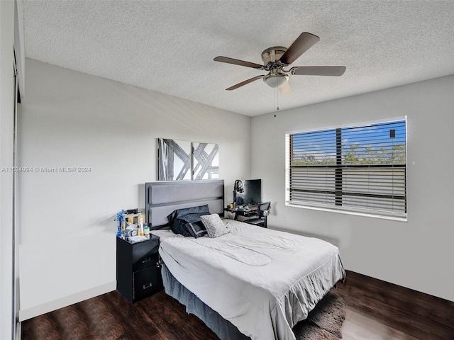 bedroom with a textured ceiling, ceiling fan, and dark hardwood / wood-style flooring