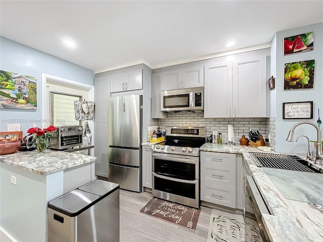 kitchen featuring light hardwood / wood-style flooring, sink, light stone counters, and stainless steel appliances