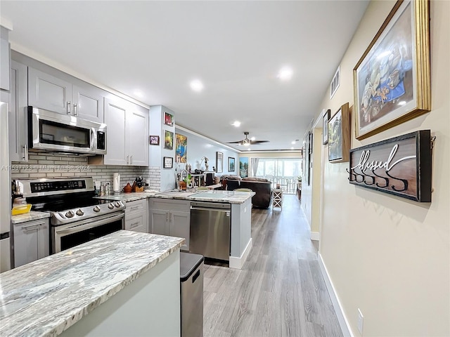 kitchen with kitchen peninsula, gray cabinetry, light hardwood / wood-style flooring, and appliances with stainless steel finishes