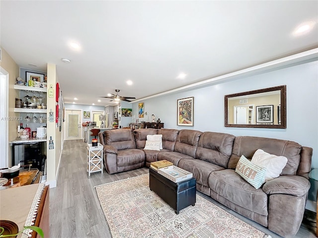 living room featuring ceiling fan, wood-type flooring, and indoor bar