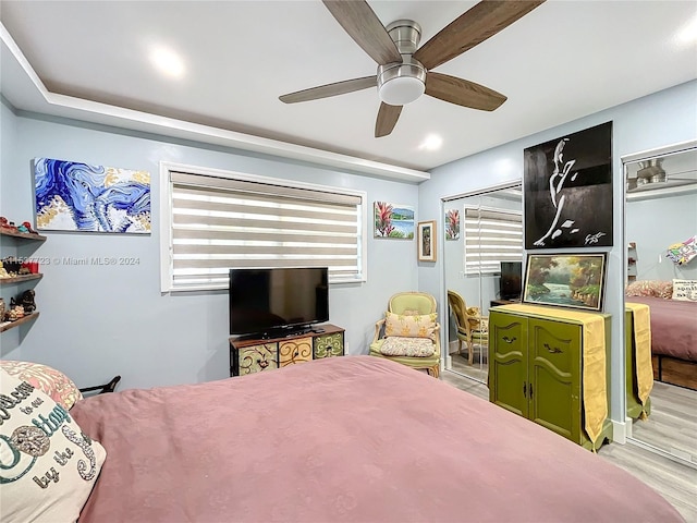 bedroom with light hardwood / wood-style flooring, ceiling fan, and a closet