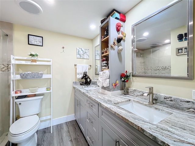 bathroom featuring wood-type flooring, vanity, toilet, and a tile shower