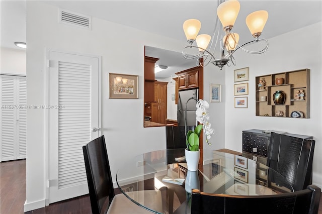 dining space featuring dark wood-type flooring and a chandelier