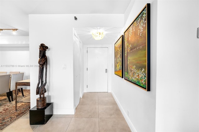 hall featuring light tile flooring and an inviting chandelier