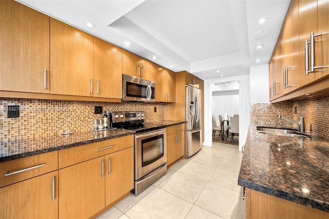 kitchen featuring backsplash, a raised ceiling, appliances with stainless steel finishes, and dark stone countertops