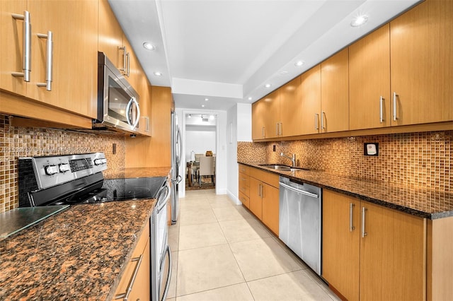 kitchen featuring light tile floors, tasteful backsplash, appliances with stainless steel finishes, a tray ceiling, and dark stone countertops