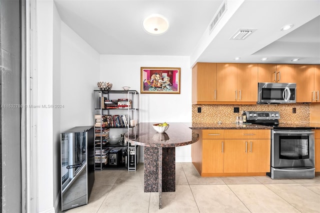 kitchen featuring dark stone countertops, tasteful backsplash, light tile floors, and stainless steel appliances