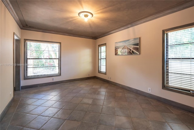 empty room with dark tile flooring, ornamental molding, and a wealth of natural light