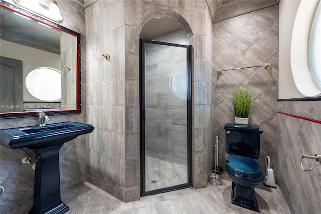 bathroom featuring a shower with door, tile floors, toilet, and tile walls