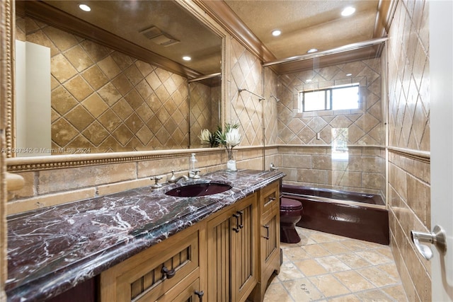 full bathroom featuring tile walls, toilet, ornamental molding, tiled shower / bath, and vanity