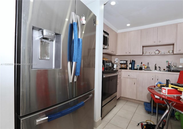 kitchen featuring light brown cabinets, ornamental molding, sink, light tile patterned floors, and appliances with stainless steel finishes