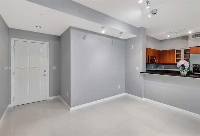 kitchen featuring rail lighting, light tile flooring, and fridge