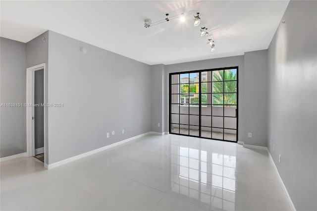 spare room featuring rail lighting and light tile flooring