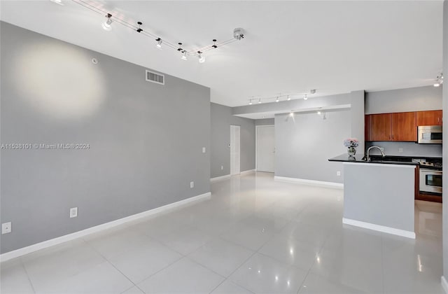 kitchen featuring light tile floors, track lighting, range, and sink