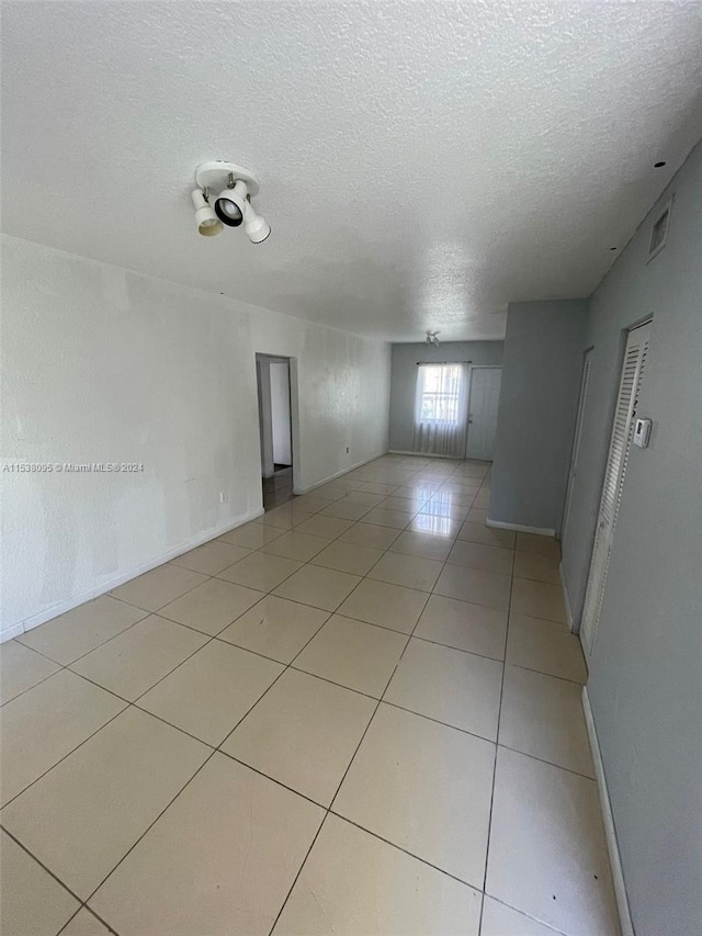 empty room featuring a textured ceiling and light tile patterned flooring