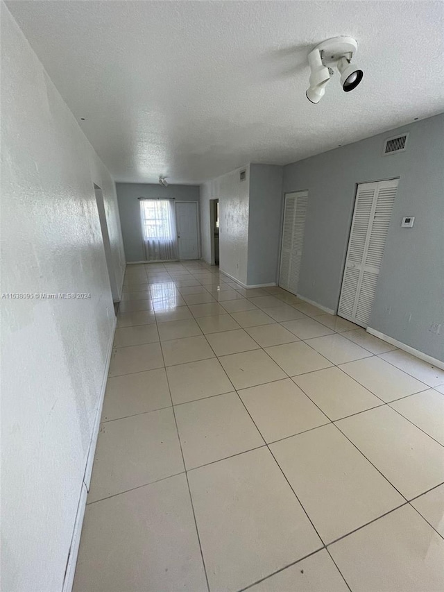 unfurnished room with a textured ceiling and light tile patterned flooring