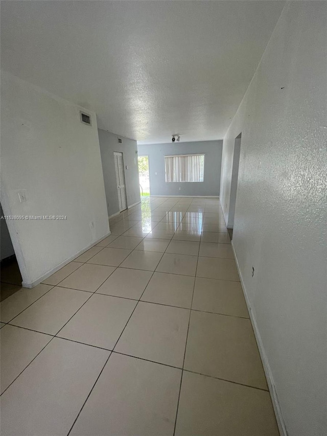 corridor featuring a textured ceiling and light tile patterned floors