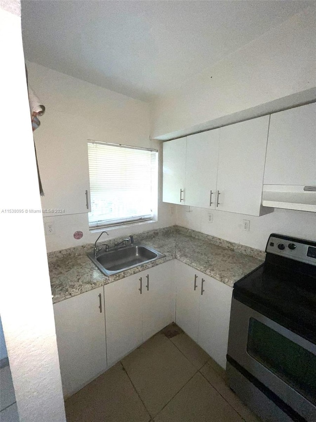 kitchen with light tile patterned floors, stainless steel electric range oven, extractor fan, sink, and white cabinets