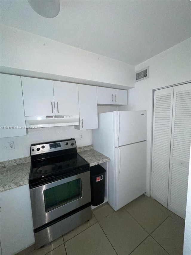 kitchen featuring stainless steel electric range, white refrigerator, light tile patterned flooring, and white cabinets