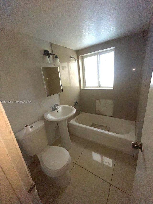 bathroom with tile patterned floors, toilet, a bathing tub, and a textured ceiling