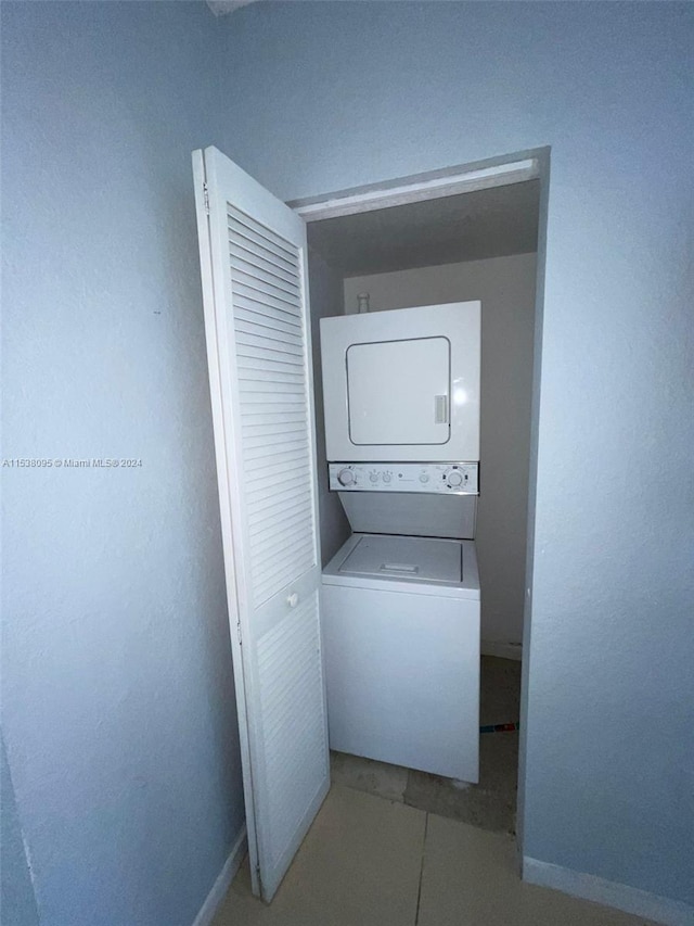 laundry room with light tile patterned floors and stacked washer / drying machine