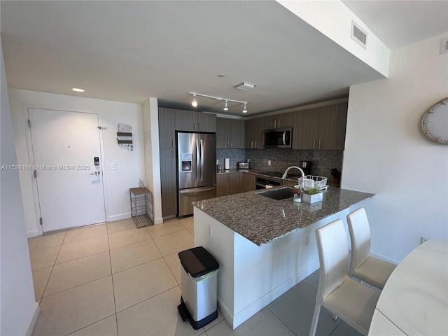 5350 NW 84th Ave Unit 1113, Doral, FL 33166 - kitchen featuring appliances with stainless steel finishes, a peninsula, tasteful backsplash, dark stone countertops, and dark brown cabinetry