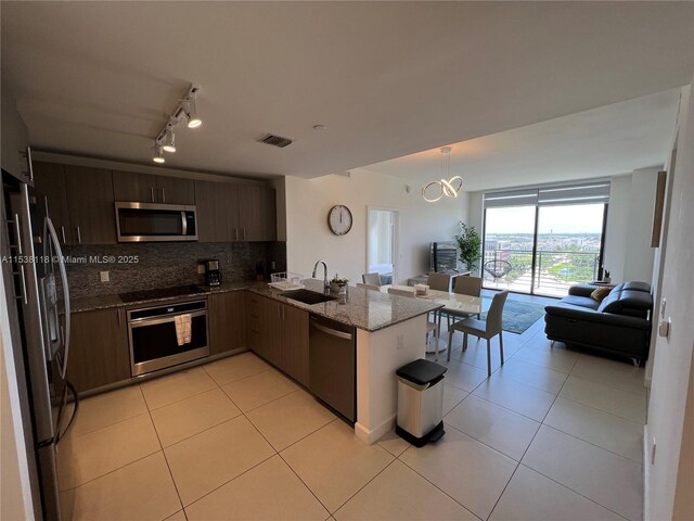 kitchen with a sink, open floor plan, light tile patterned floors, and stainless steel appliances