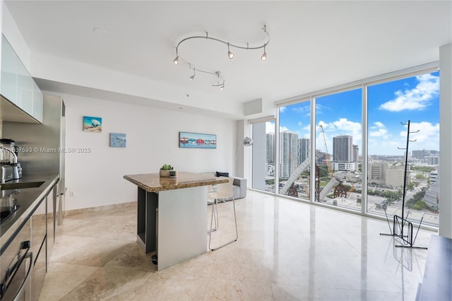 kitchen featuring floor to ceiling windows, white cabinetry, a breakfast bar, and dark stone counters