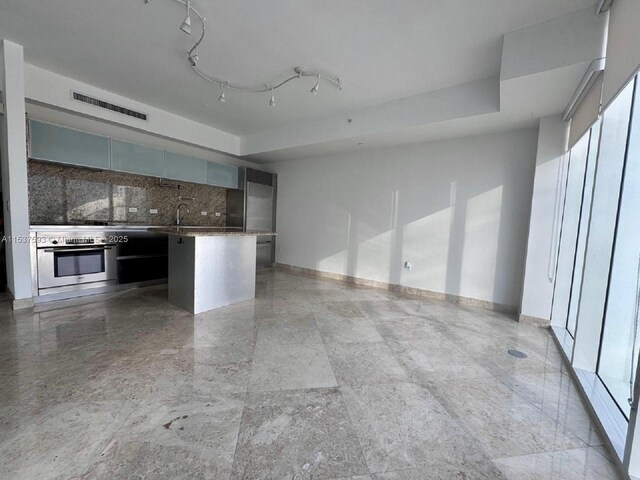 kitchen with a kitchen breakfast bar, stainless steel oven, kitchen peninsula, and backsplash