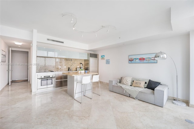 living room with a tray ceiling and sink