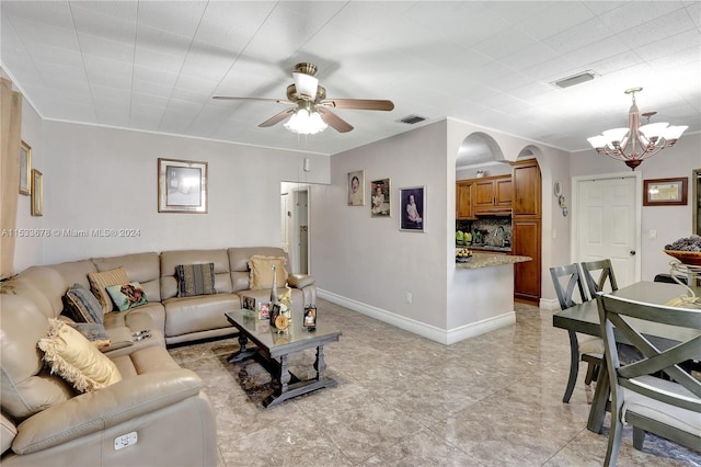 living room with light tile flooring, crown molding, and ceiling fan with notable chandelier