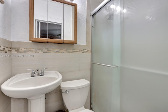 bathroom featuring tile walls, a shower with shower door, and toilet