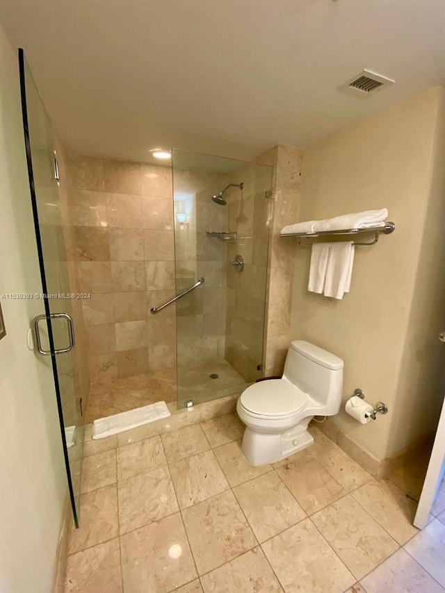 bathroom featuring toilet and a shower with shower door