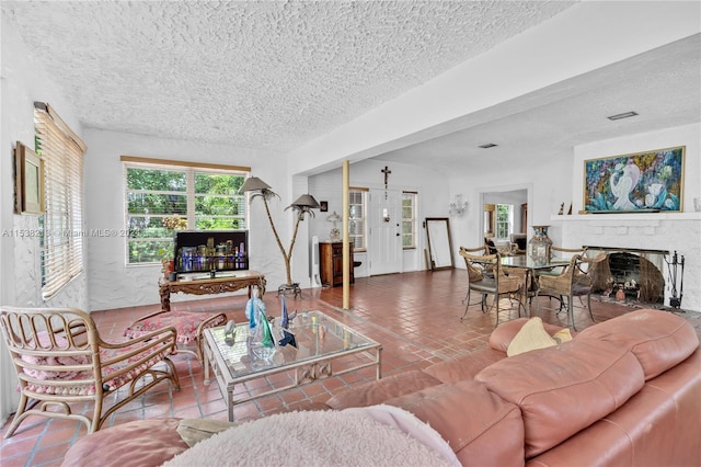 living room with tile patterned flooring, a textured ceiling, and a brick fireplace