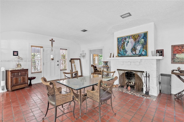 dining area with a textured ceiling and a fireplace