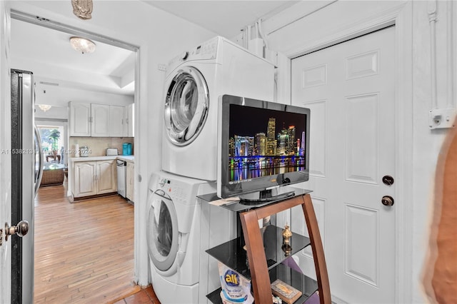 laundry area featuring stacked washing maching and dryer and light hardwood / wood-style flooring