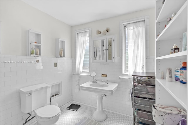 bathroom featuring tile patterned flooring, toilet, and tile walls